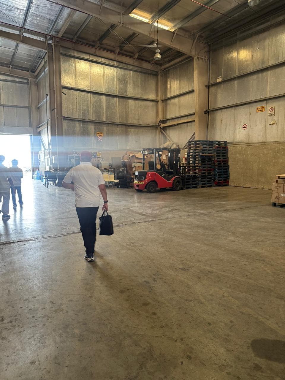 Walking into a warehouse in the industrial belt during a field visit, a forklift and stacked pallets ahead.