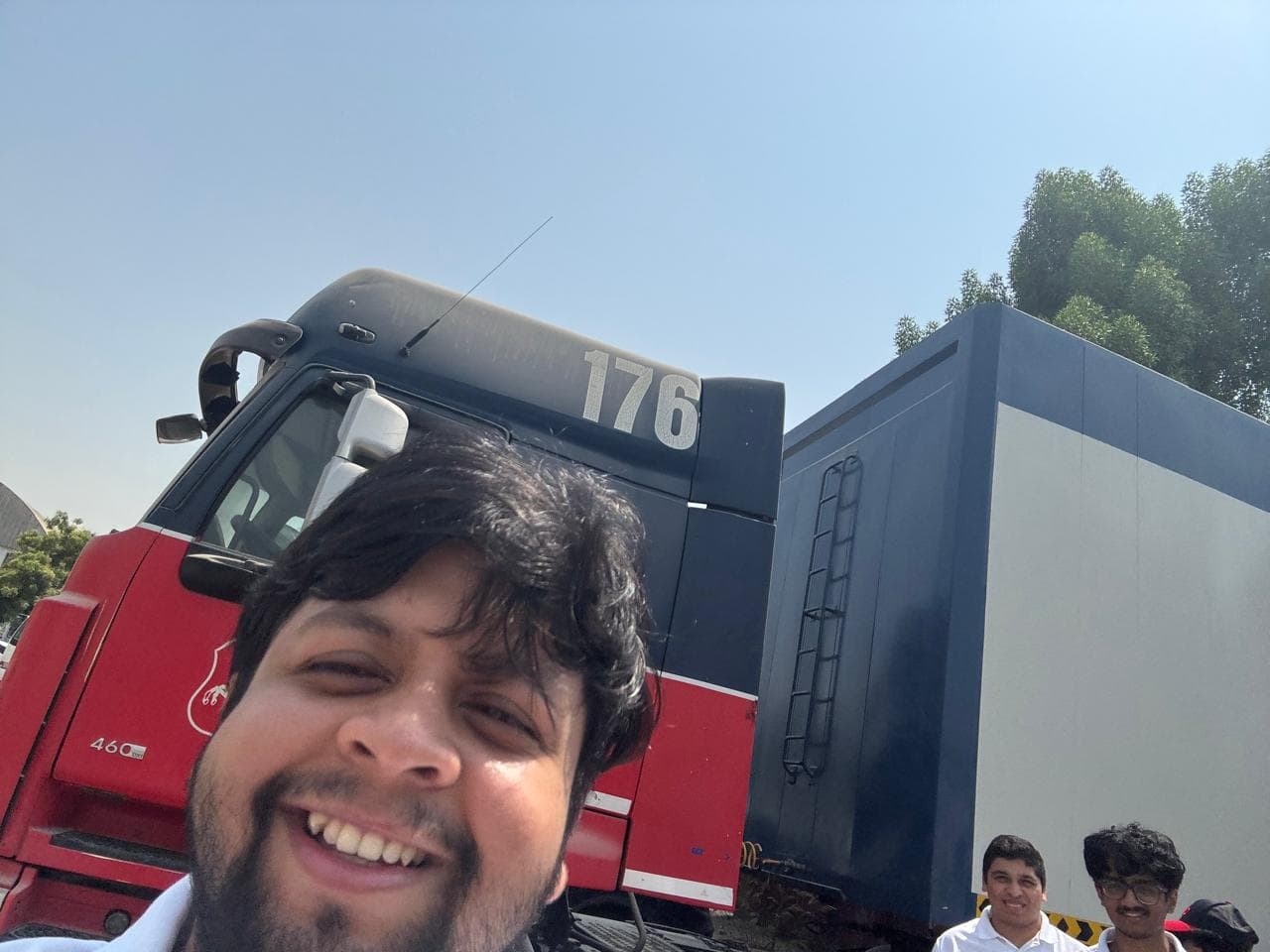 Beside a red Volvo tractor unit during fieldwork in the industrial corridor.